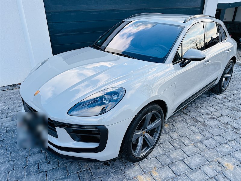 Weißer SUV mit spiegelnder Windschutzscheibe vor einem Garagentor